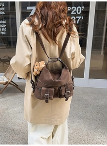 Rear view of a model wearing a dark brown vintage backpack with a cute bear charm