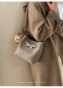 Detail of grey lychee leather bucket bag with silver buckle and cute bear pendant charm