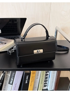 Détail d'un sac à main minimaliste en cuir noir mat avec fermoir rotatif en métal argenté