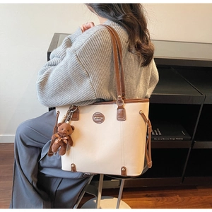 Detail of minimalist tote bag with contrast trim and cute brown teddy bear charm