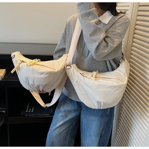 Detail of minimalist cream crescent bag with textured fabric and woven rope zipper pull