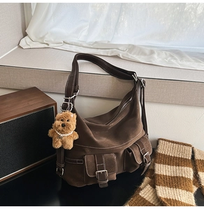 Detail of dark coffee vintage shoulder bag with contrast stitching and bear charm