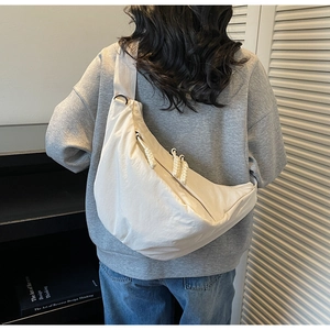 Detail of cream nylon crossbody bag with knotted zipper and textured pleated finish