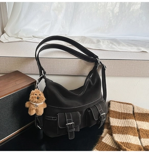 Detail of black tote bag with white stitching, dual front pockets and puppy charm