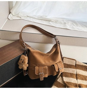 Detailed close-up of brown matte leather tote bag with white contrast stitching and pockets