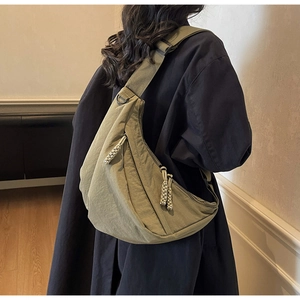 Olive green crescent crossbody bag with woven zipper on a model for casual commuting