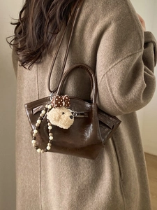 Dark brown patent bucket bag with plush puppy charm and metallic twist lock detail