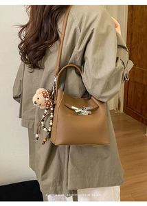 Detail of retro brown litchi pattern bucket bag with bear pendant and metal buckle
