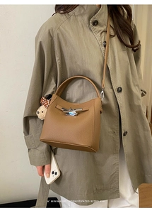 Detail of retro brown lychee leather bucket bag with silver buckle and bear charm accessory