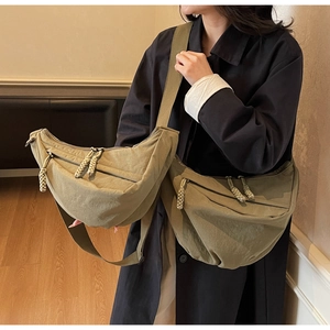 Detailed comparison of army green crescent crossbody bag sizes on a model