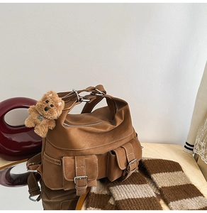 Close-up of brown suede tote bag with white contrast stitching and a cute bear charm
