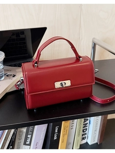 Gros plan d'un sac cartable vintage en cuir bordeaux avec fermoir argenté sur un bureau