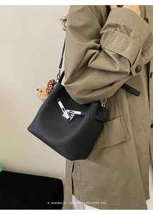 Detail of black lychee grain bucket bag featuring silver buckle and cute bear charm