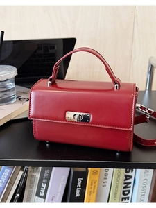 Détail du sac à main rouge verni avec fermoir rotatif argenté et poignée solide
