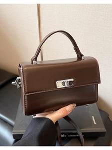 Détail du sac à main en cuir marron foncé avec fermoir rotatif argenté et coutures précises