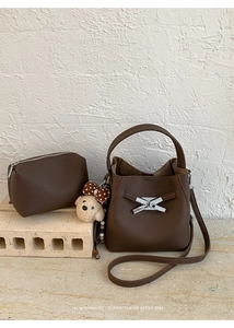 Close-up of brown litchi pattern bucket bag with bear pendant and matching small pouch