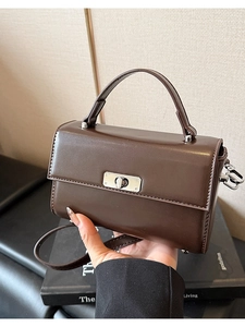 Détail d'un sac à bandoulière carré marron foncé avec fermoir rotatif en métal argent