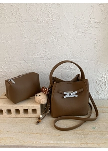 Detail of dark brown lychee texture leather bucket bag with silver bow and plush bear