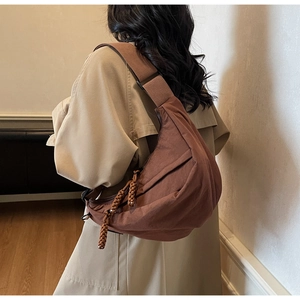 Detail of a brown nylon crescent crossbody bag with wide strap and braided zipper pulls