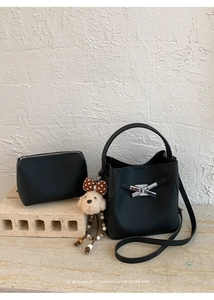 Detail of black lychee grain leather bucket bag set with silver buckle and puppy charm