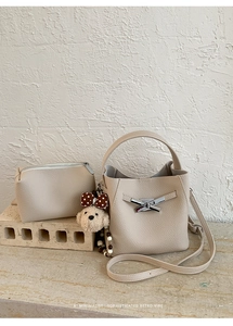 Close-up of beige lychee grain bucket bag with matching pouch and plush puppy charm