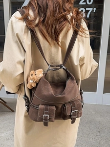 Deep brown vintage tote bag with contrast stitching and plush bear charm on model