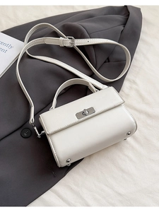 Détail d'un sac carré blanc en similicuir avec fermoir rotatif argenté et bandoulière