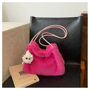 Dettaglio ravvicinato di una borsa a secchiello in peluche rosa con ciondolo mostro bianco