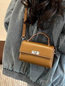 Sacoche en cuir PU marron avec poignée et fermoir argenté sur fond de veste en jean