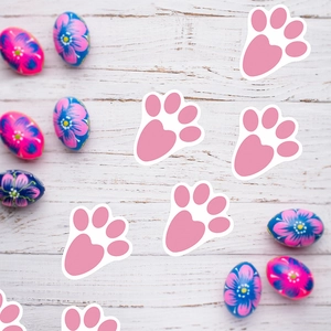 Pink rabbit paw Happy Easter stickers on white wooden background with festive eggs decoration