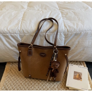 Detail of vintage brown suede tote with leather handles and decorative bear pendant
