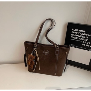 Detailed view of dark coffee tote bag with white contrast stitching and plush bear charm