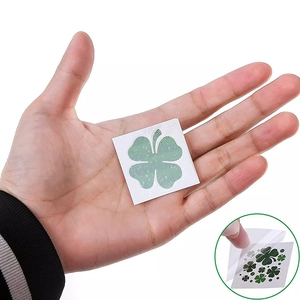 Close-up of green shamrock tattoo stickers with glitter texture on a hand