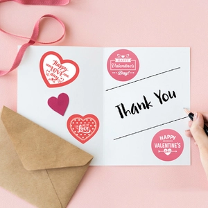 Valentine's Day heart stickers on white greeting card with pink envelopes and ribbons