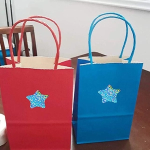 Detail of red and blue gift bags with holographic star stickers and twisted handles