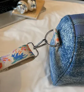 Detail of silver metallic hook on denim cylinder bag with ethnic woven shoulder strap