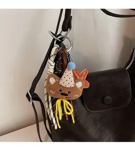 Close-up of a cute plush bear bag charm with a party hat and braided cord detail