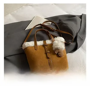 Detail showing plush trim and suede texture of a brown bucket bag on grey suit fabric