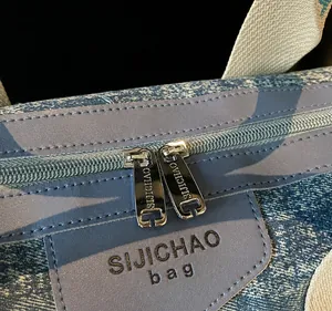 Detail of dual metal zippers and denim fabric texture on a casual fashion handbag