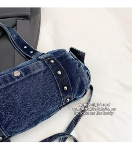 Dettaglio della borsa in denim blu scuro con borchie in metallo argento e cuciture rifinite