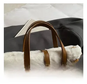 Close-up of caramel faux suede handbag with plush white fur trim and leather handle