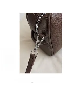 Detailaufnahme von dunkelbraunem Leder mit Lychee-Maserung und silbernem Metallreißverschluss