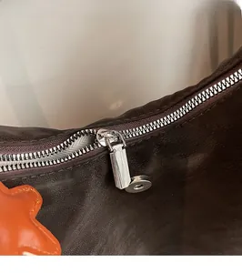 Detail of silver metal zipper and dark brown textured leather on large backpack