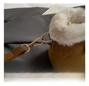 Detail of golden metal hook on brown suede shoulder bag with white faux fur trim
