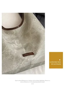 Detail of grey textured fabric tote bag with brown leather trim and brand logo patch