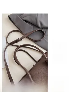 Detail der dunkelbraunen Litschi-Ledertasche mit verstellbarem Gurt und Narbenstruktur