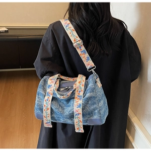 Close-up of washed denim tote bag featuring ethnic style embroidery wide straps and hardware
