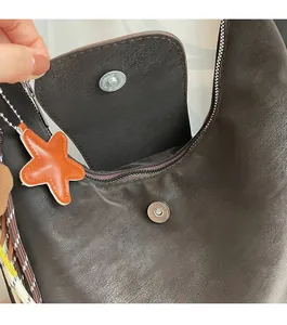 Macro shot of vintage brown leather tote bag with magnetic closure and star charm