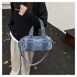 Dettaglio borsa a cilindro in denim lavato con borchie argentate e tracolla street style