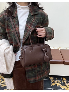 Dettaglio della borsa marrone scuro in pelle martellata con manici e scritta moda